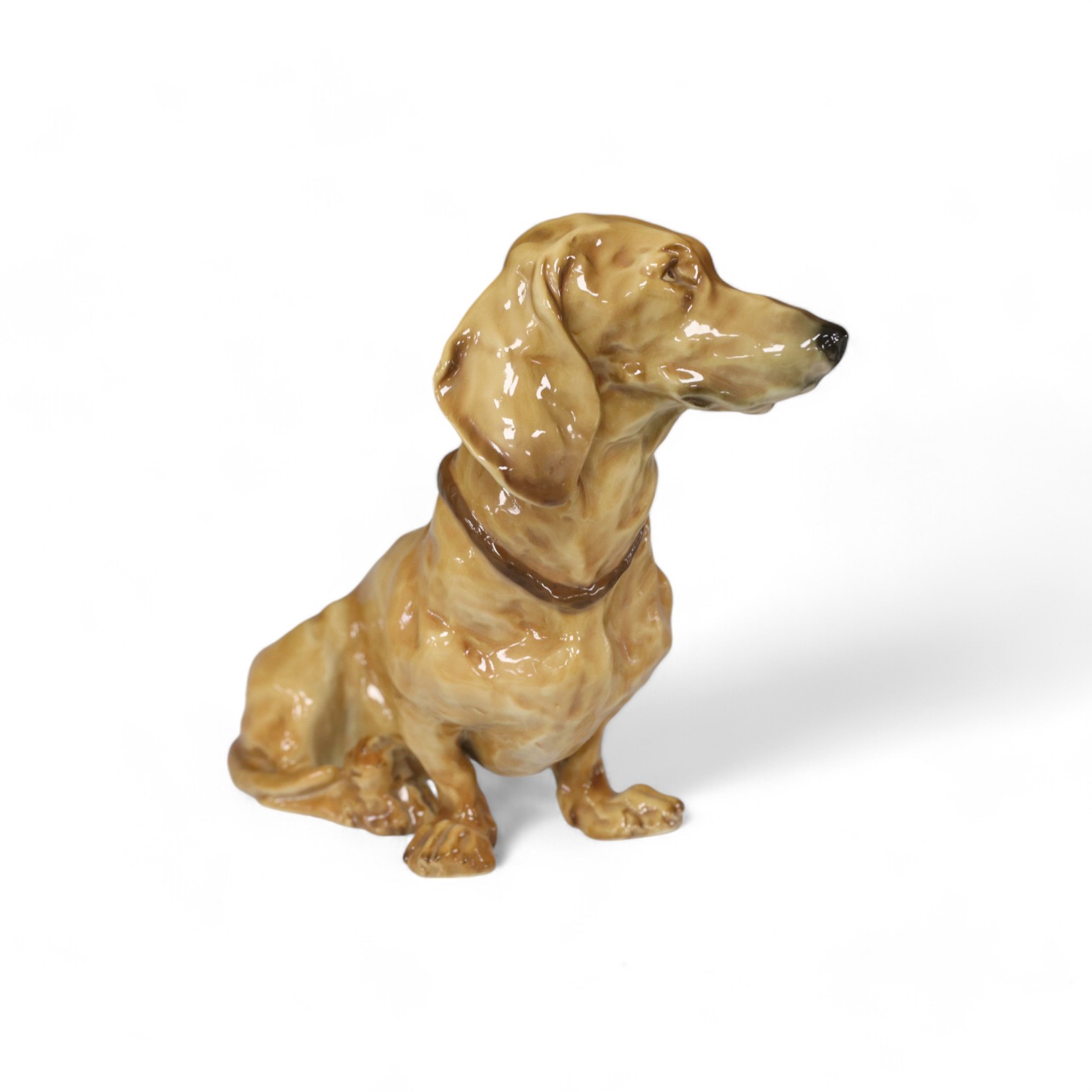 A Nymphenburg seated dachshund, 19.5cm high. Condition - small firing crack to edge otherwise good